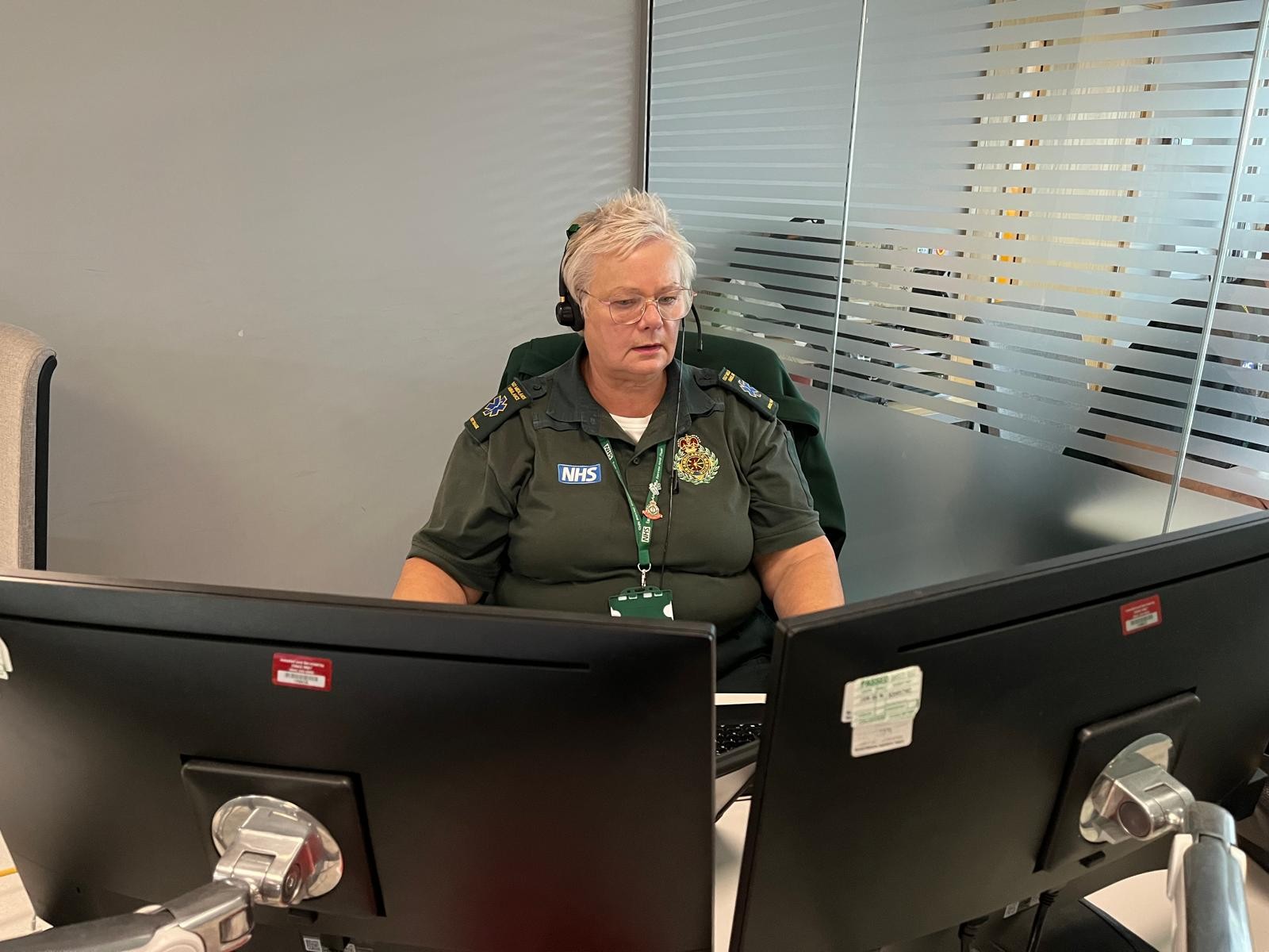 Ann at work in Clinical Hub. She is sat in front of her screens with a headset on.
