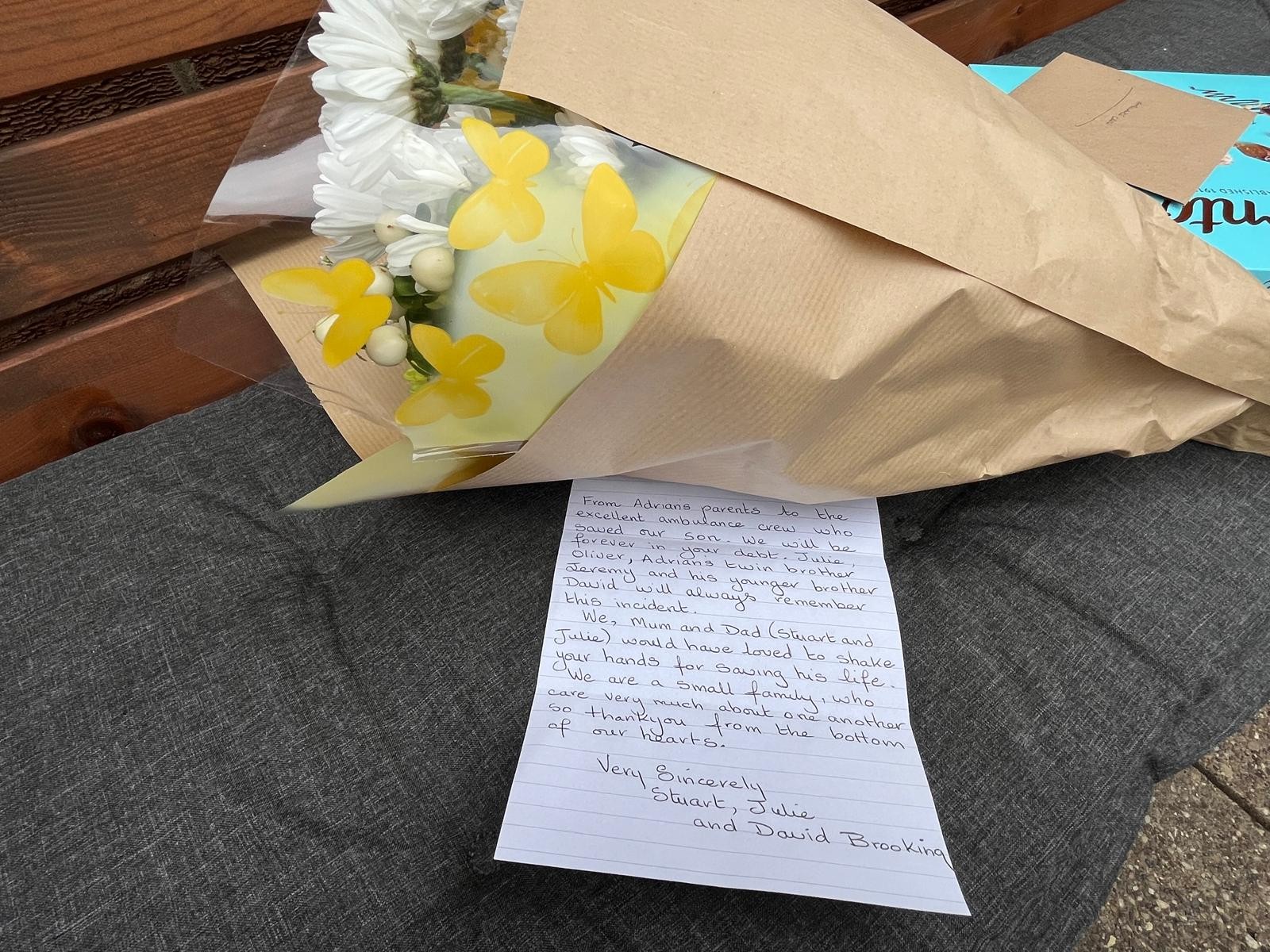 A handwritten letter from Adrian's parents by a bouquet of flowers