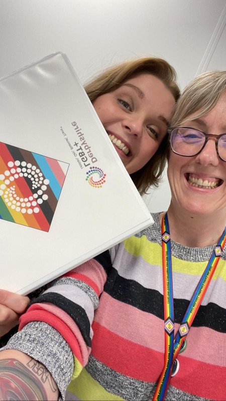 Two women proudly display the rainbow accreditation, signifying support for the LGBT+ community at EMAS.
