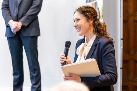 Joy Weldin opening the award ceremony. She is talking into a microphone.