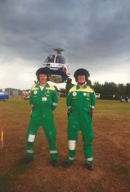 Nick Sentence and a colleague pictured in front of an air ambulance. The rotas of the air ambulance are rotating very fast.